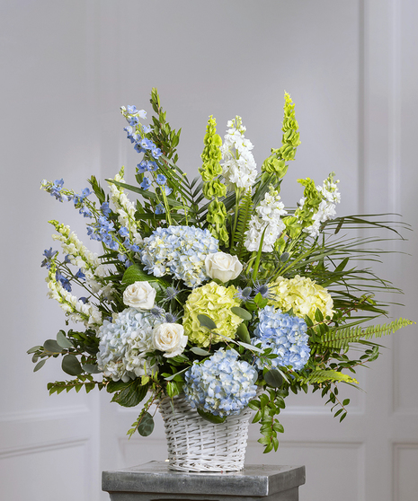 Blue & White Garden Sympathy Basket featuring hydrangea, delphinium, roses, stock and lush foliage