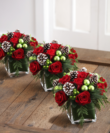 The Christmas Delight Bouquet features red roses, glass ornaments, and snow tipped cones in scented christmas greens.