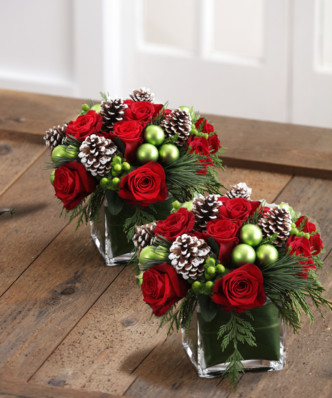 The Christmas Delight Bouquet features red roses, glass ornaments, and snow tipped cones in scented christmas greens.