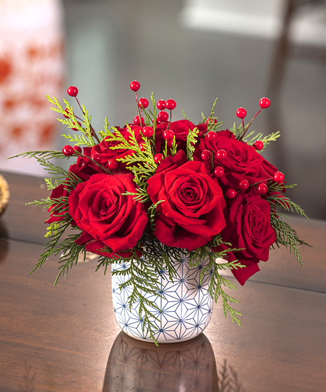 Christmas Cheer Bouquet featuring red roses and holiday foliage in a keepsake container