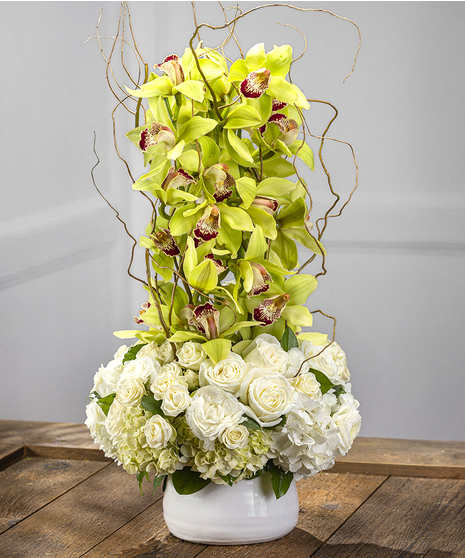 The Manhattan features exotic orchids amid southern hydrangeas and roses in a white ceramic container. 