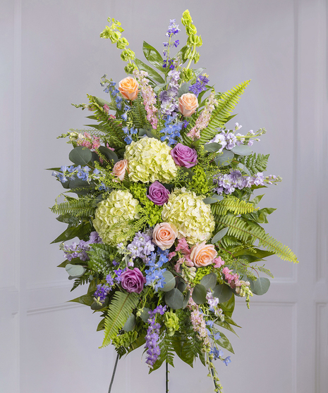 Pastel Garden Standing Sympathy Spray featuring kiwi hydrangea, mountain roses, larkspur, delphinium on a standing easel
