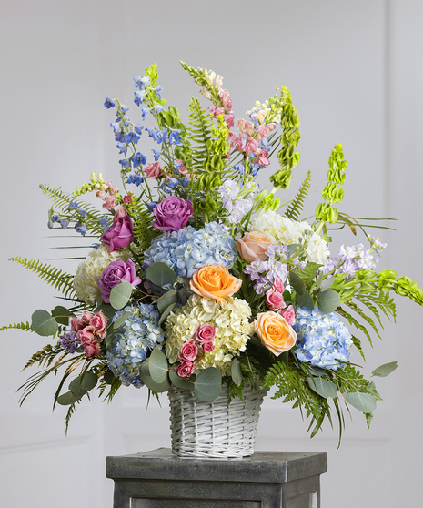 Pastel Garden Sympathy Basket featuring hydrangea, stock, snapdragons, delphinium, and orchids in a wicker basket