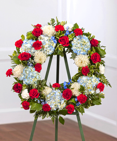 Patriot Garden Sympathy Wreath featuring hydrangea, roses, delphinium and foliage on a standing easel
