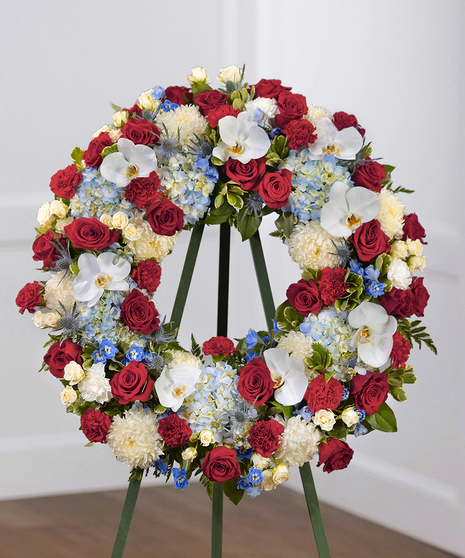 Patriot Garden Sympathy Wreath featuring hydrangea, roses, delphinium and foliage on a standing easel