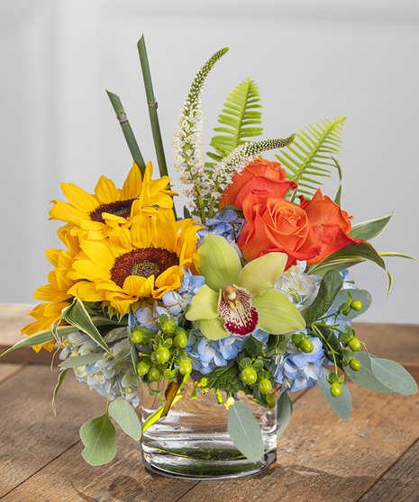 Morningside Park features blue hydrangea, orange roses, yellow sunflowers, veronica and an exotic orchid.