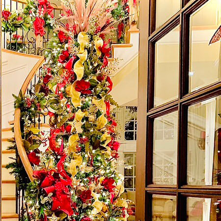 A beautifully decorated Christmas tree, with gold and red ribbons, inside a residential home